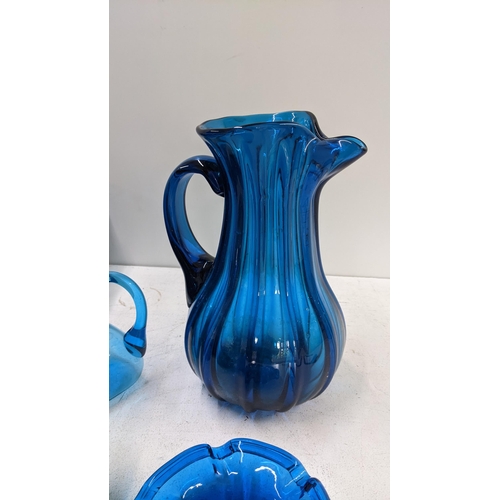 119 - A collection of mixed blue art glassware to include a pitcher, ash tray, vase with matching tumblers... 