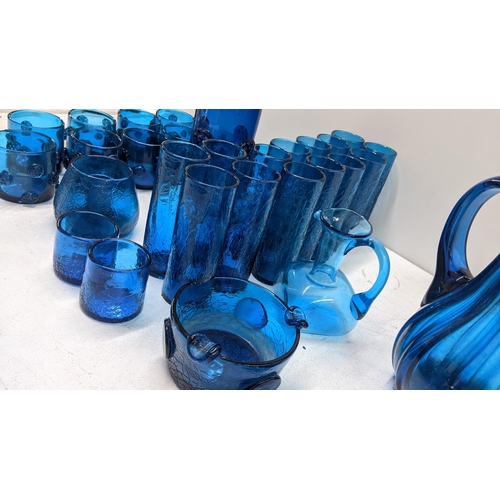 119 - A collection of mixed blue art glassware to include a pitcher, ash tray, vase with matching tumblers... 