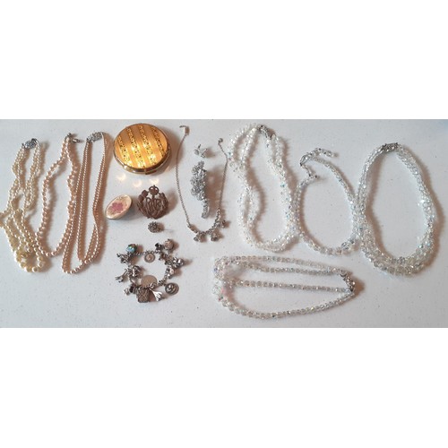 86 - A quantity of vintage costume jewellery to include a silver and white metal charm bracelet having a ... 