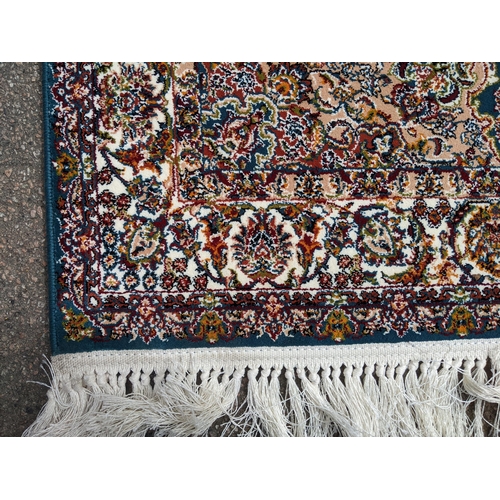 423 - A modern machine woven Persian style rug, ornate design on a dark turquoise ground, triple guard bor... 