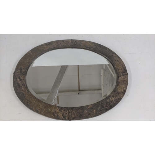 107 - An Arts & Crafts oval wall hanging mirror made from tin, having a hammered design, together with one... 