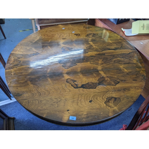 343 - A mid Victorian rosewood circular dining table with splayed legs and a fitted shelf underneath, on c... 