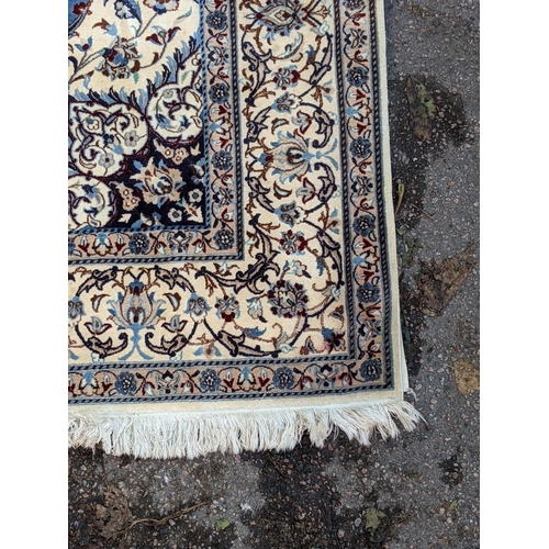 349 - A Persian hand knotted rug with a cream border with repeating motifs and a symmetrical star and surr... 