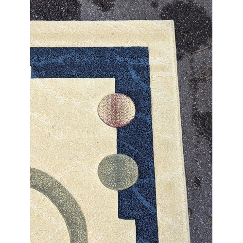 350 - A modern hand knotted rug with a symmetrical abstract design with a blue border, central swirl emble... 