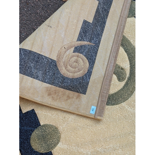 350 - A modern hand knotted rug with a symmetrical abstract design with a blue border, central swirl emble... 