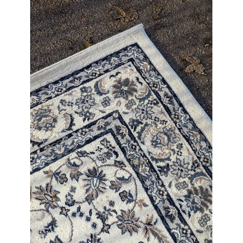 351 - A modern machine made rug with abstract floral decoration, repeating blue border on a cream backgrou... 