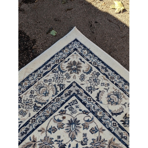 351 - A modern machine made rug with abstract floral decoration, repeating blue border on a cream backgrou... 