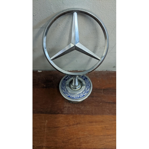 302 - Two bonnet ornaments to include a Rolls Royce flying lady and a Mercedes Benz three pointed star
Loc... 