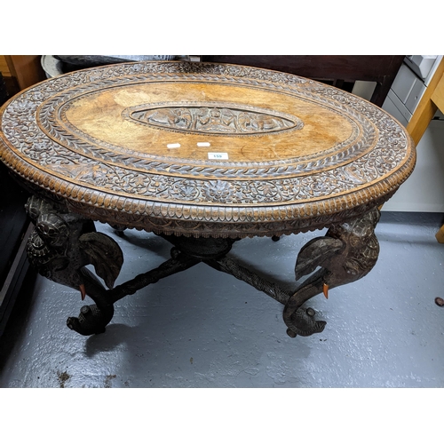 159 - An early 20th century Indian carved hardwood elephant coffee table, the oval top with central carved... 