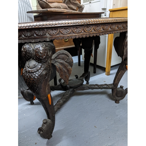 159 - An early 20th century Indian carved hardwood elephant coffee table, the oval top with central carved... 