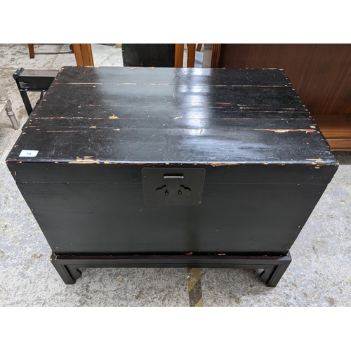 74 - An early to mid 20th century Asian ebonized chest on stand with side carrying handles, 62