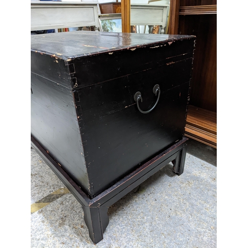 74 - An early to mid 20th century Asian ebonized chest on stand with side carrying handles, 62