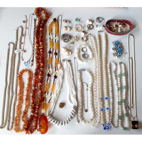 125 - A quantity of costume jewellery to include a rough cut amber necklace, a modern amber necklace A/F, ... 