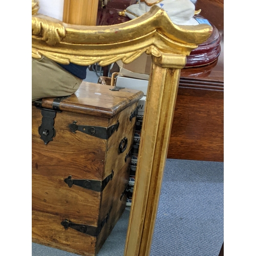 468 - A gilt framed overmantel mirror decorated with gold coloured gilding with a central emblem at the to... 