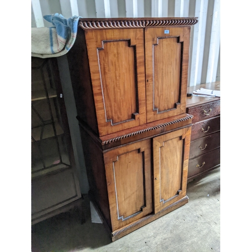 514 - A 19th century mahogany cabinet with a gadrooned cornice over four panelled doors, each enclosing sh... 