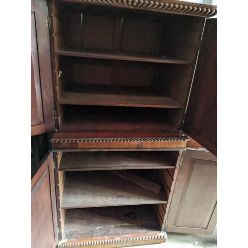 514 - A 19th century mahogany cabinet with a gadrooned cornice over four panelled doors, each enclosing sh... 