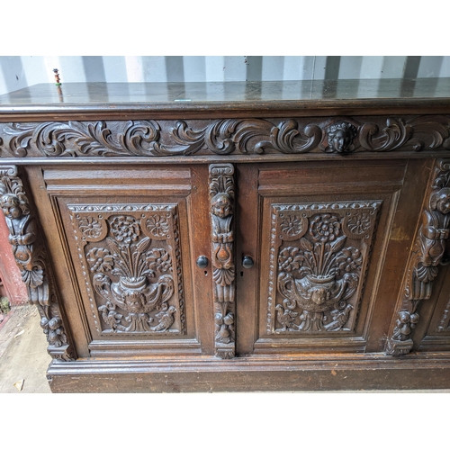 531 - An early 20th century oak sideboard with carved ornament, and three doors on a plinth, 99cm h x 181c... 