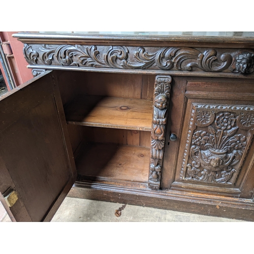 531 - An early 20th century oak sideboard with carved ornament, and three doors on a plinth, 99cm h x 181c... 