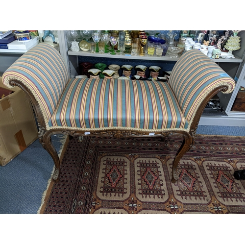 565 - An early 20th century French style walnut window seat with scrolled ends and carved ornament, on cab... 