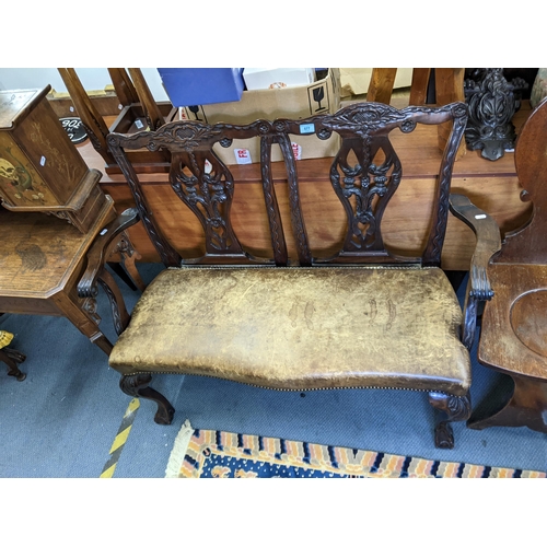 577 - A 1920's mahogany Chippendale style double chair back sofa, with carved splats, leather seat on cabr... 