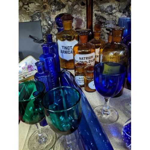 444 - A collection of glassware, mainly blue glass, and amber coloured chemist bottles to include a blue g... 