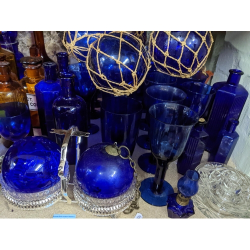 444 - A collection of glassware, mainly blue glass, and amber coloured chemist bottles to include a blue g... 