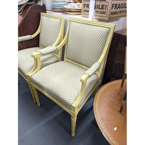 469 - A pair of pale yellow painted French style armchairs upholstered in floral fabric raised on tapering... 