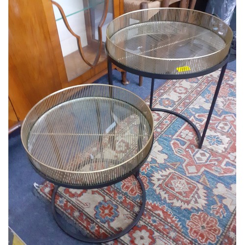 197 - A modern duo of circular nesting tables having removable gold and glass galleried tops set in black ... 