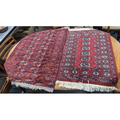 214 - Three rugs to include a hand woven red ground rug with elephant foot motif and multiguard borders, 1... 