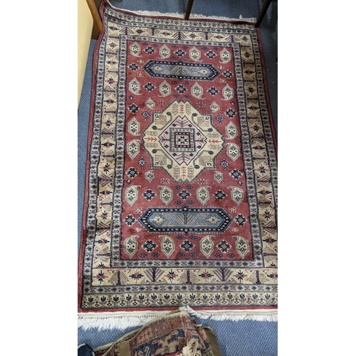 214 - Three rugs to include a hand woven red ground rug with elephant foot motif and multiguard borders, 1... 