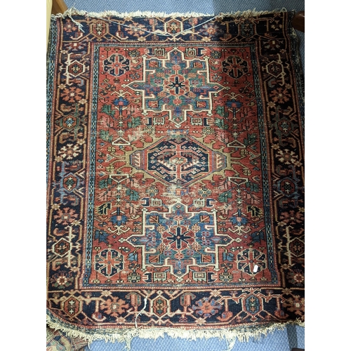 215 - Four rugs to include a Persian Heriz red ground rug with repeating motifs, 129cm x 107cm 
Location:A... 