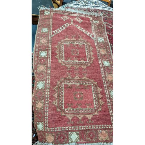 215 - Four rugs to include a Persian Heriz red ground rug with repeating motifs, 129cm x 107cm 
Location:A... 