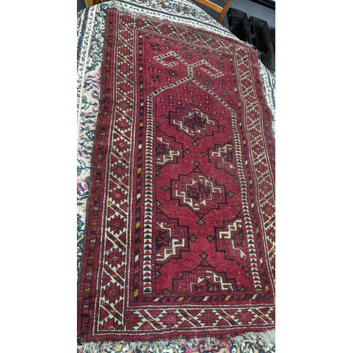 215 - Four rugs to include a Persian Heriz red ground rug with repeating motifs, 129cm x 107cm 
Location:A... 