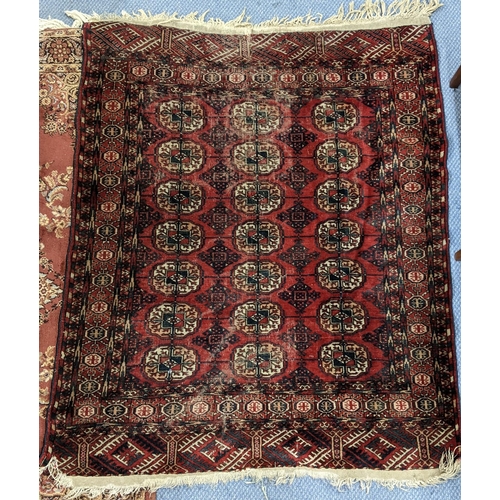 216 - A Pakistani red ground rug having elephant foot motifs and multiguard borders with tasselled ends, 1... 