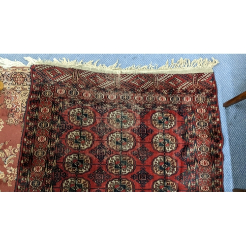 216 - A Pakistani red ground rug having elephant foot motifs and multiguard borders with tasselled ends, 1... 