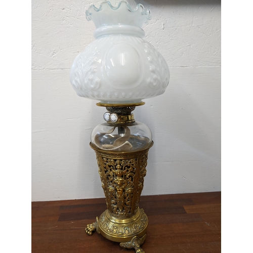 360 - A late 19th century brass oil lamp with an opaque glass shade, pierced figure and scrolled ornament ... 