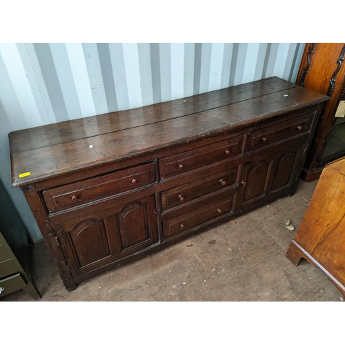 377 - A 17th century style oak dresser with three inline drawers, twin panelled doors and two drawers, 82c... 