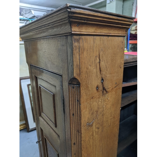 447 - A 19th century oak narrow side cabinet, two panel doors flanked by fluted edges, shaped interior she... 