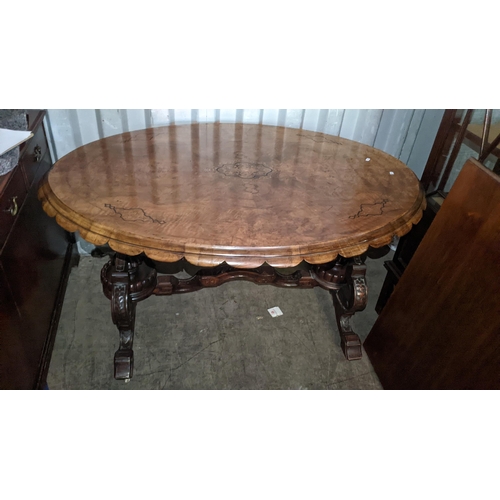 522 - A Victorian quarter cut veneered walnut oval loo table having marquetry inlaid and carved legs unite... 