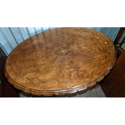 522 - A Victorian quarter cut veneered walnut oval loo table having marquetry inlaid and carved legs unite... 