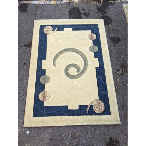 492 - A modern hand knotted rug with a symmetrical abstract design with a blue border, central swirl emble... 