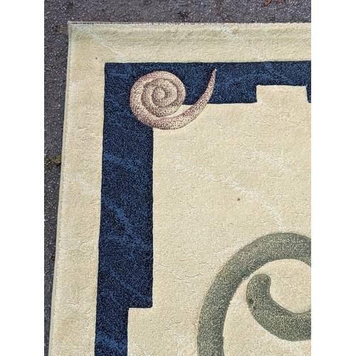 492 - A modern hand knotted rug with a symmetrical abstract design with a blue border, central swirl emble... 