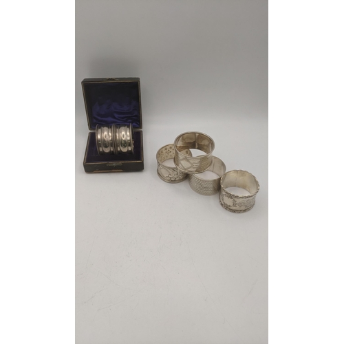 115 - Six silver napkin rings to include a pair in a fitted case, a floral embossed example, two engraved ... 