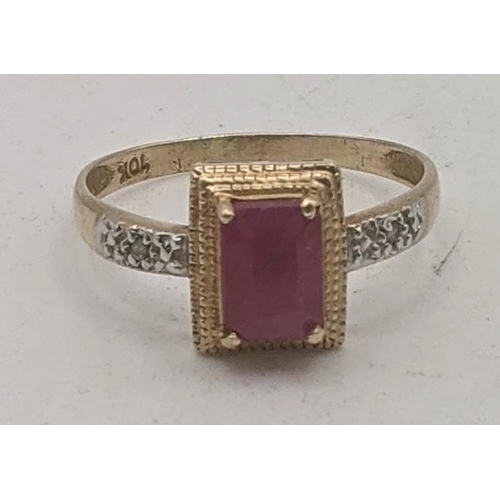 152 - A yellow gold ring stamped 10K having an emerald cut ruby in four-claw setting flanked by two small ... 