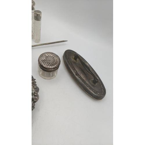 134 - Silver dressing table items to include two silver lidded scent bottles and pot, a nail buffer and a ... 