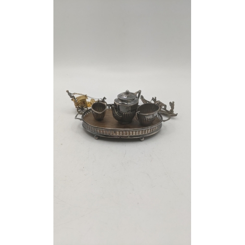 136 - A silver miniature three-piece tea service to include a teapot, sugar bowl, milk jug, and silver pie... 