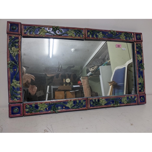 269 - A contemporary studio pottery framed wall mirror decorated with trailing flower buds and leaves in r... 