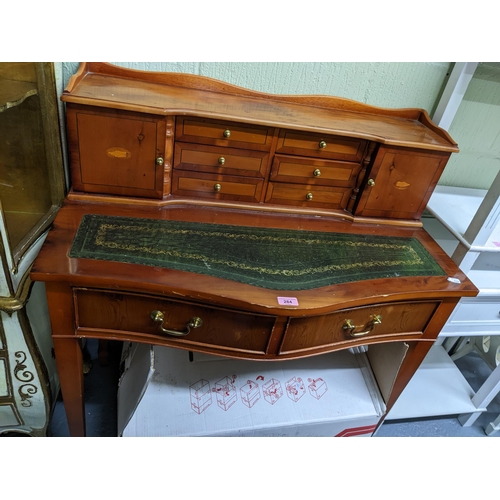 284 - A 20th century yew wood serpentine fronted writing desk with six central drawers flanked by twin cup... 