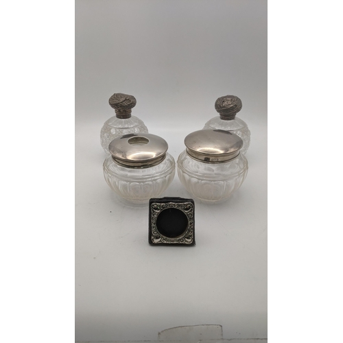 58 - Silver topped dressing table items to include two crystal cut glass scent bottles A/F tow jars along... 