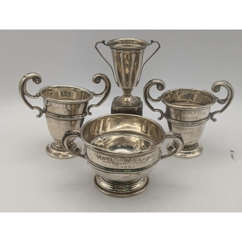 62 - Four silver trophy cups three inscribed to Matlock gold club along with one other example on a pedes... 